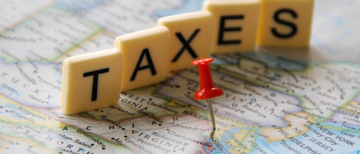 Red push pin marking Washington DC in map word taxes in letter tiles for tax filing season